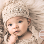 Baby in tan knit hat, lying on pillow.