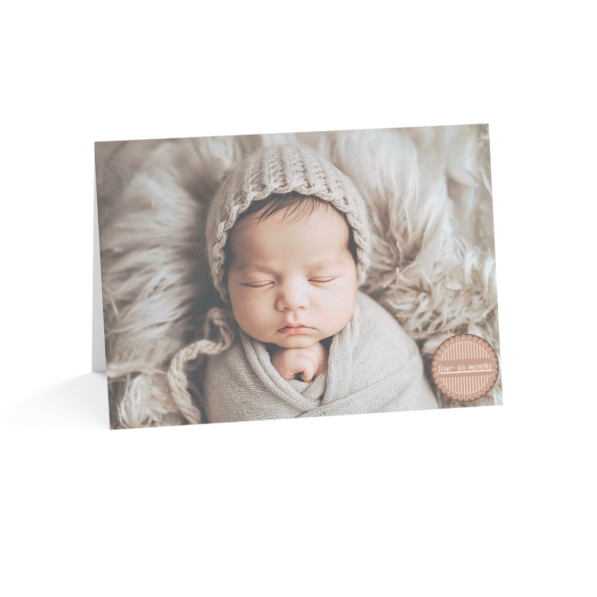 Picture of Caucasian Baby Card 4-6 Months with baby wearing a knit hat on a beige blanket with the words four-six months in a medallion on the front of the card.