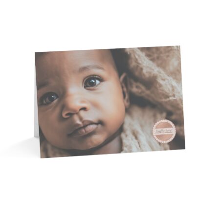 Finally Here card with Picture of an African American appearing baby in a beige blanket with the words Finally Here in a medallion on the front of the card.